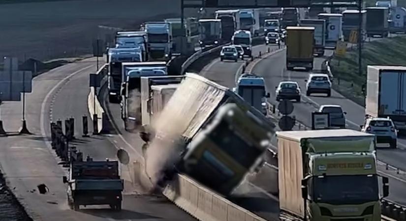 Durva baleset az M1-esen: fennakadt a betonfalon és az oldalára borult egy kamion – videó
