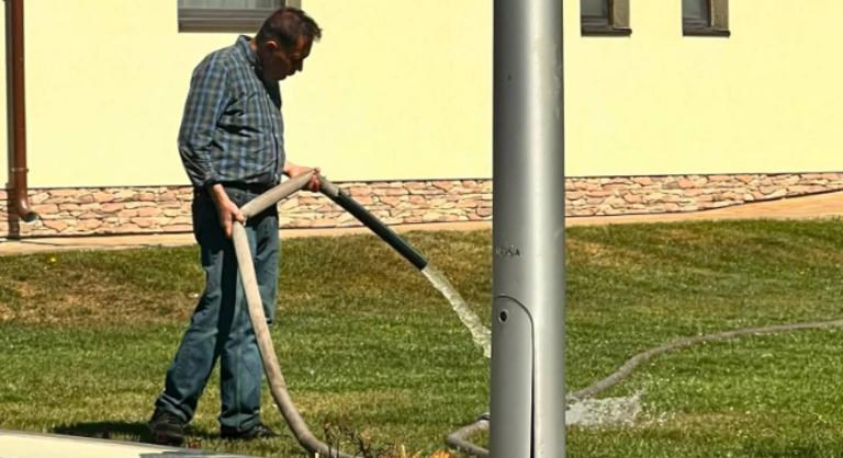 A vízhiány közepette lefotózták Pócs Jánost, amint tűzoltó slaggal öntözi a gyepet