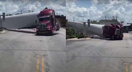 Videón, ahogy egy szélturbina lapátját szállító teherautó elakad egy vasúti átjáróban