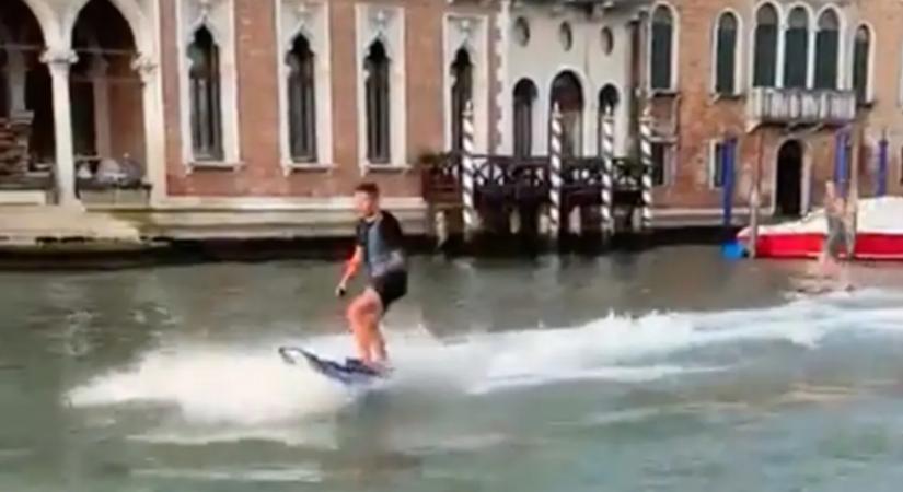 Videón, ahogy két szörfös szlalomozik a velencei gondolák között