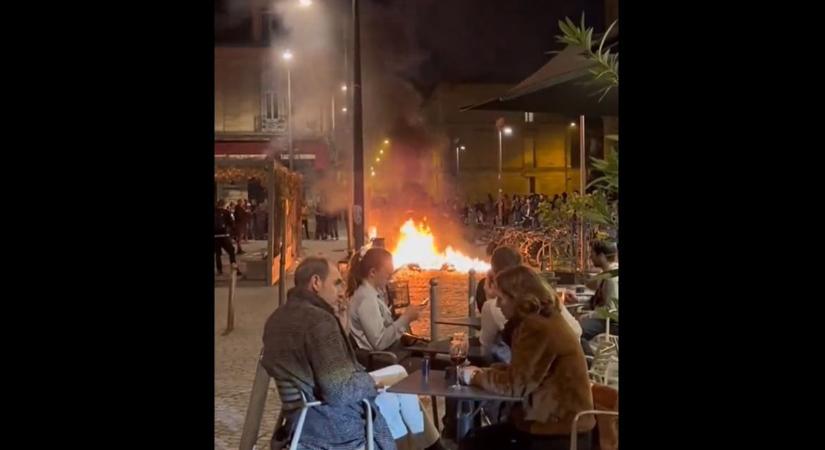 Szürreális jelenet Franciaországból: lángokban áll az utca, közben az emberek nyugodtan kávézgatnak a teraszokon (VIDEÓ) (videó)