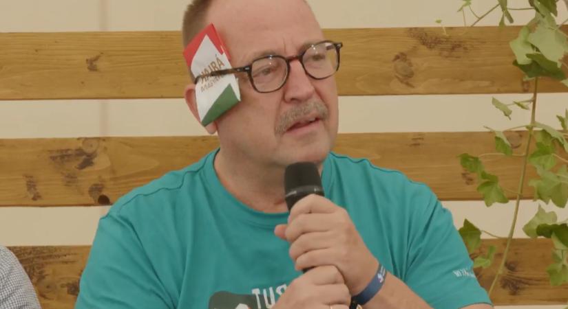 Németh Zsolt a Trump-merénylet ellen tiltakozva "Hajrá magyarok" feliratú papírdarabot rakott a füle mellé Tusványoson