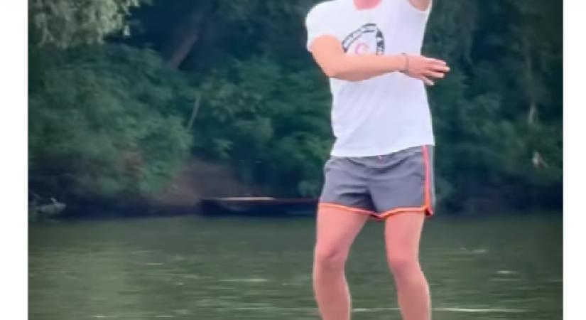 Magyar Péter a tiszalöki vízierőműnél, rövidgatyában, mezítláb nyomja a csónak orrán táncolós mémet