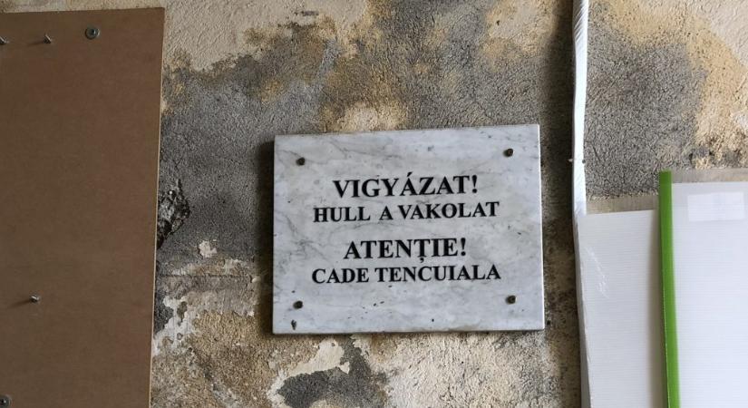 Szürreál: Emléktáblának tűnő felirat figyelmeztet a vakolathullásra Sepsiszentgyörgyön