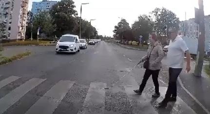 Videón látható, ahogy egy pécsi buszsofőr kísér át egy látássérült hölgyet a zebrán