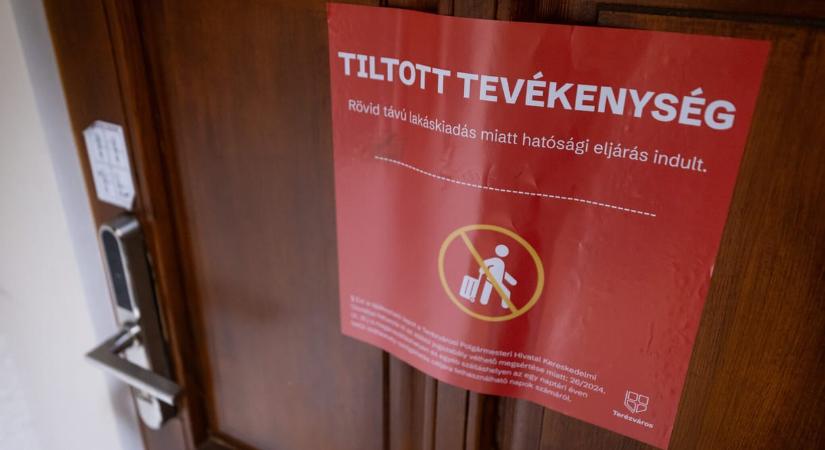 Piros hatósági plakátot ragaszt Terézváros a tiltás ellenére működő Airbnb-szállásokra