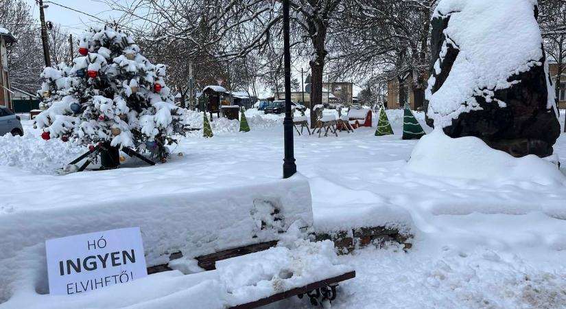 Hirdetés jelent meg egy hóbucka tetején, fotózkodnak vele a helyiek