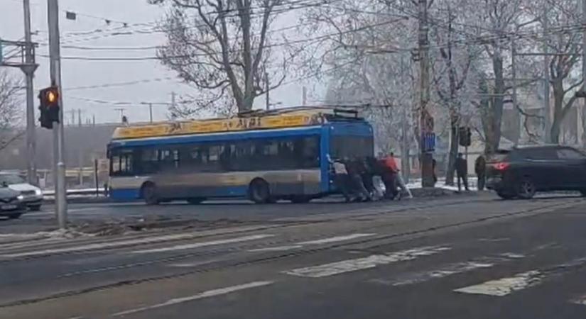 Videón, ahogy a leállt trolibuszt az utasok tolják ki a kereszteződésből Debrecenben