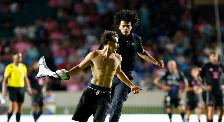 Videón, ahogy Lionel Messi félmeztelen fanatikusa a pályára rohan, majd a világsztárral együtt földre kerül