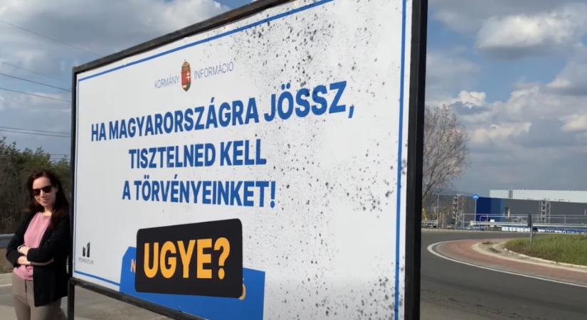 Korábbi nemzeti konzultációs üzenetet tartalmazó plakáttal tiltakozik a Momentum a gödi Samsungnál