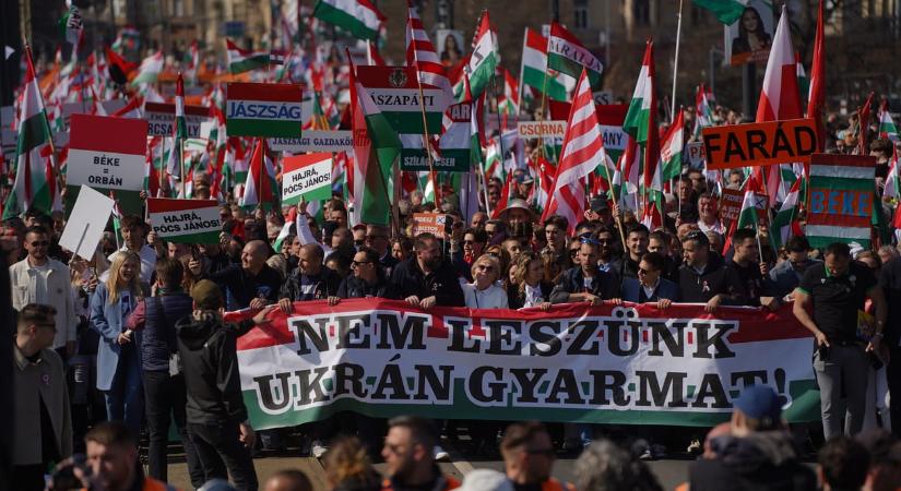 „Nem leszünk ukrán gyarmat” feliratú molinóval vonulnak a békemenetelők a Kossuth térre