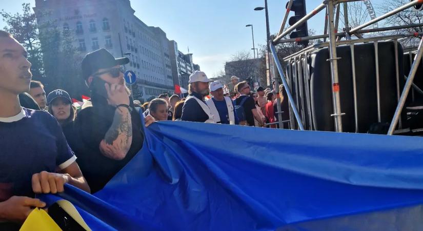 A Tisza felvonulásába ukrán zászlót becipelő csoport két tagját lefényképezték, ahogy az „ukrán háborús menetről” szóló molinót lógatják le egy házról